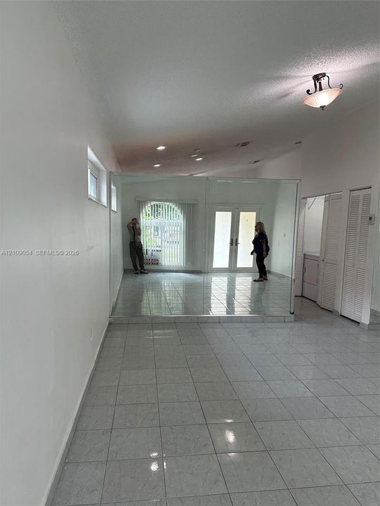 Interior space featuring vaulted ceilings, floor-to-ceiling mirrored walls, ceramic tile flooring, recessed lighting, and double-door glass entry
