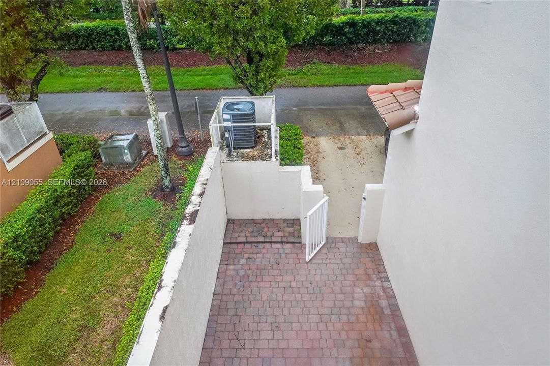 Enclosed patio featuring brick pavers, white privacy walls, and a gated entrance