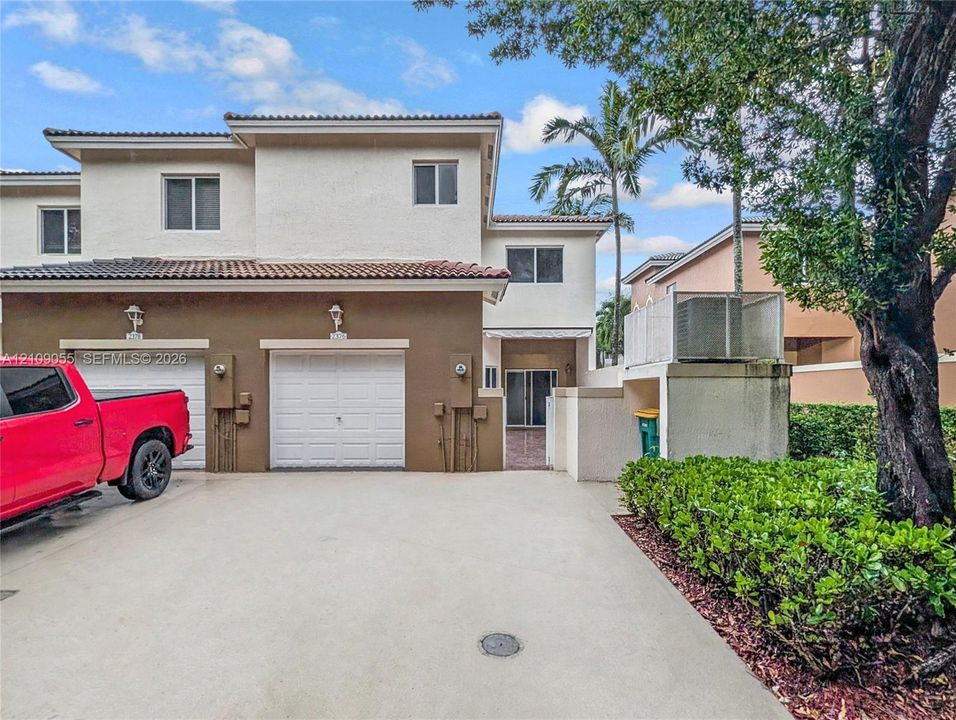 Two-story exterior featuring a stucco facade, dual-bay garage, concrete driveway, and attached wall-mounted lighting