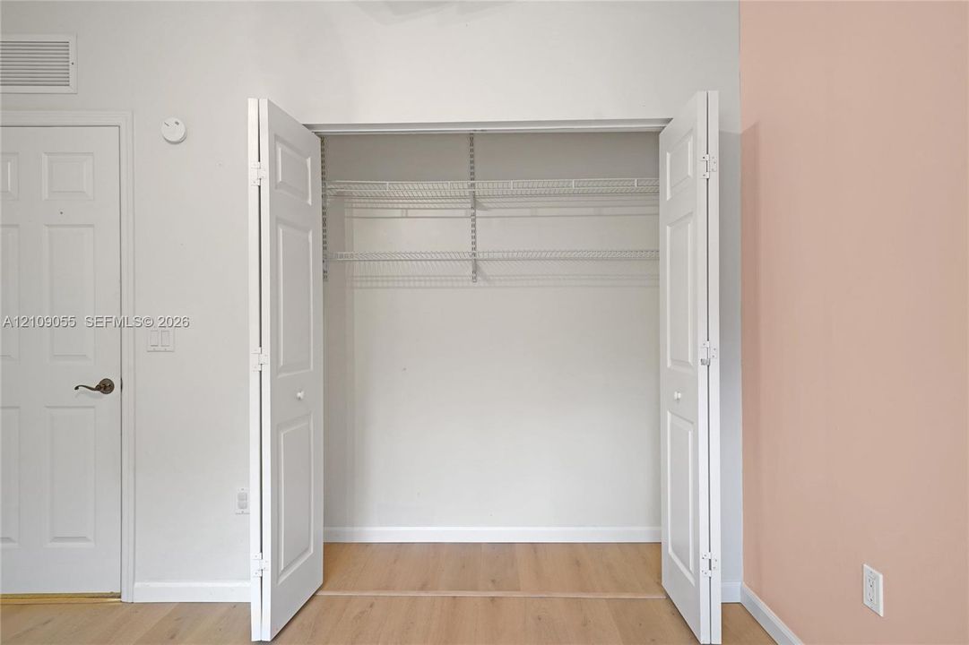 Bi-fold closet doors featuring wire shelving and wood-finish flooring