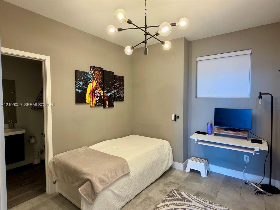 Modern multi-arm sputnik-style chandelier, wall-mounted floating desk, stone-finish tile flooring, and roller shade window treatment