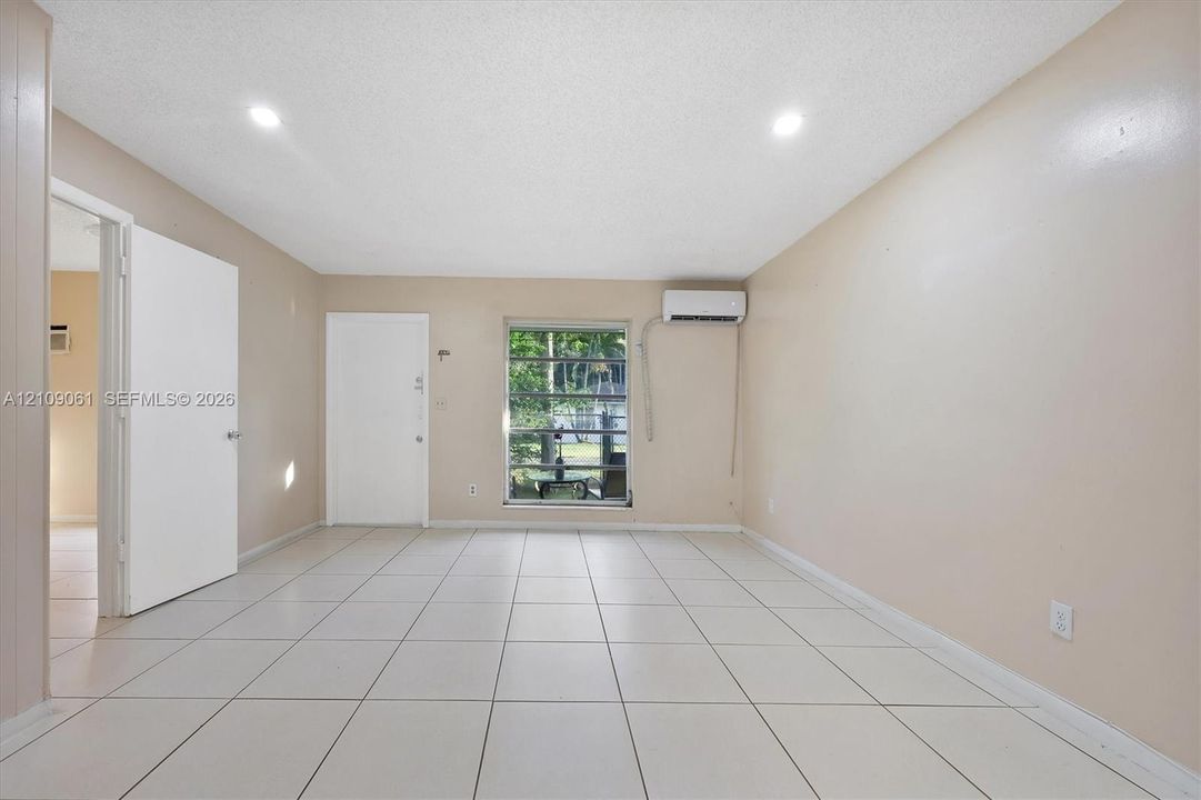 Interior space featuring large-format tile flooring, recessed ceiling lighting, and wall-mounted ductless climate control unit