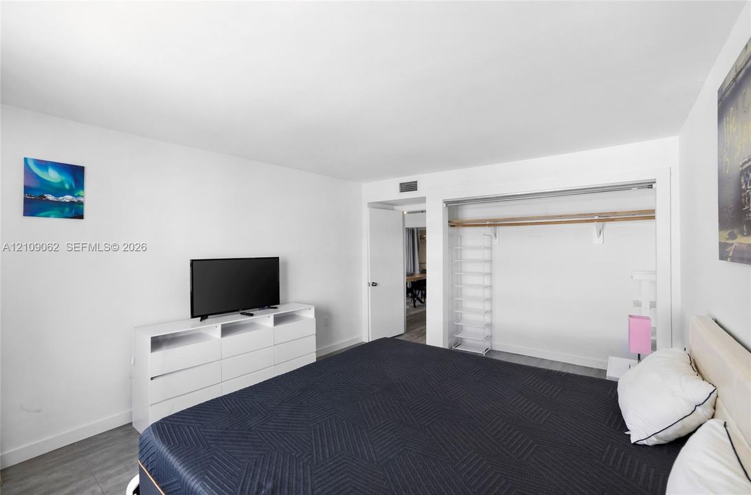 Interior space featuring wood-finish flooring, smooth wall surfaces, and a reach-in closet with integrated shelving and rod