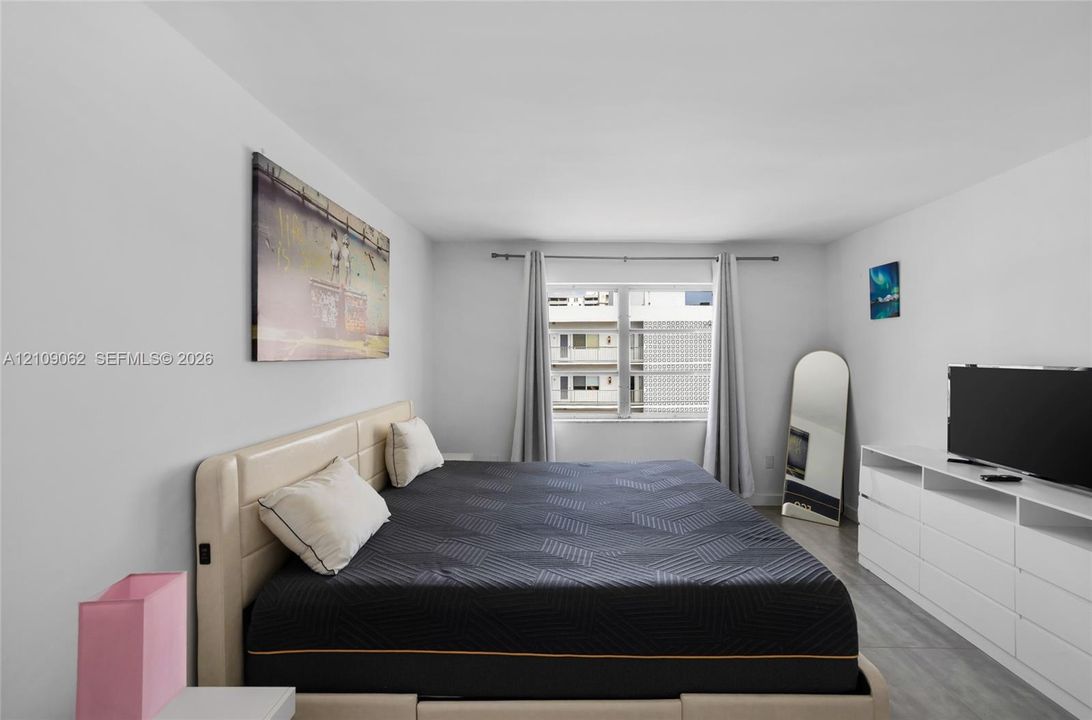 Neutral-toned interior space featuring light-colored wall finish, wood-finish flooring, and a large multi-pane window with metal hardware