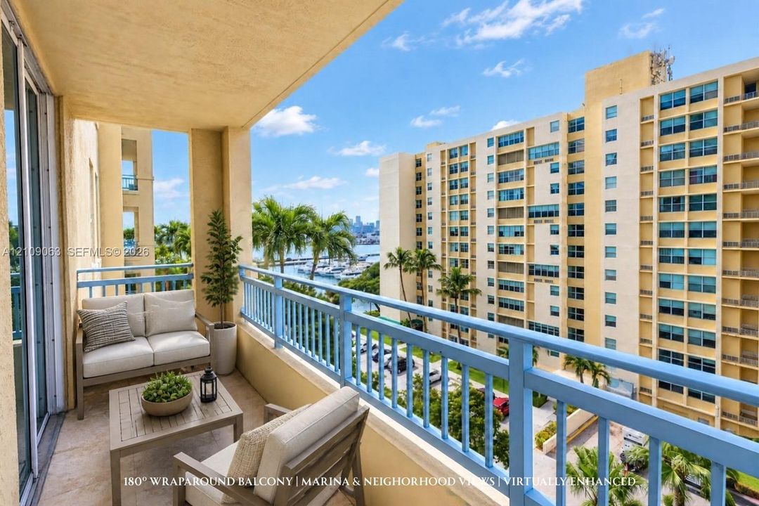Covered balcony with a protective blue railing, stone-finish flooring, and a backdrop of marina and neighborhood scenery