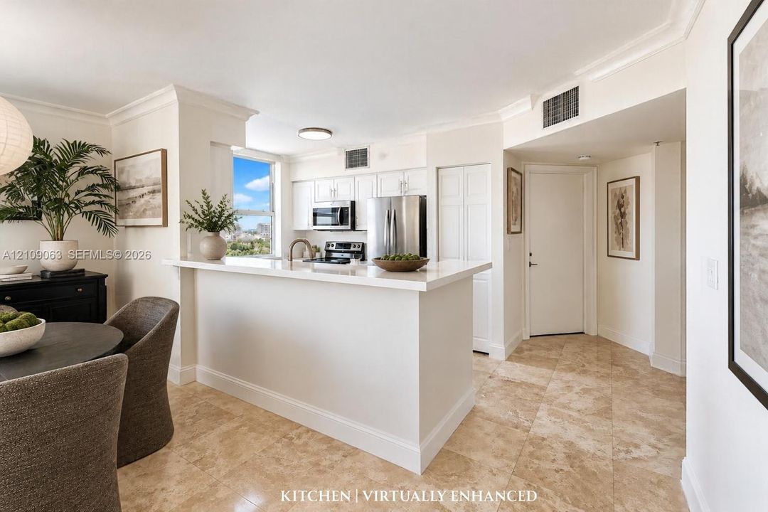 Kitchen featuring white cabinetry, solid-surface countertops with a breakfast bar, stainless steel appliances, and tile flooring
