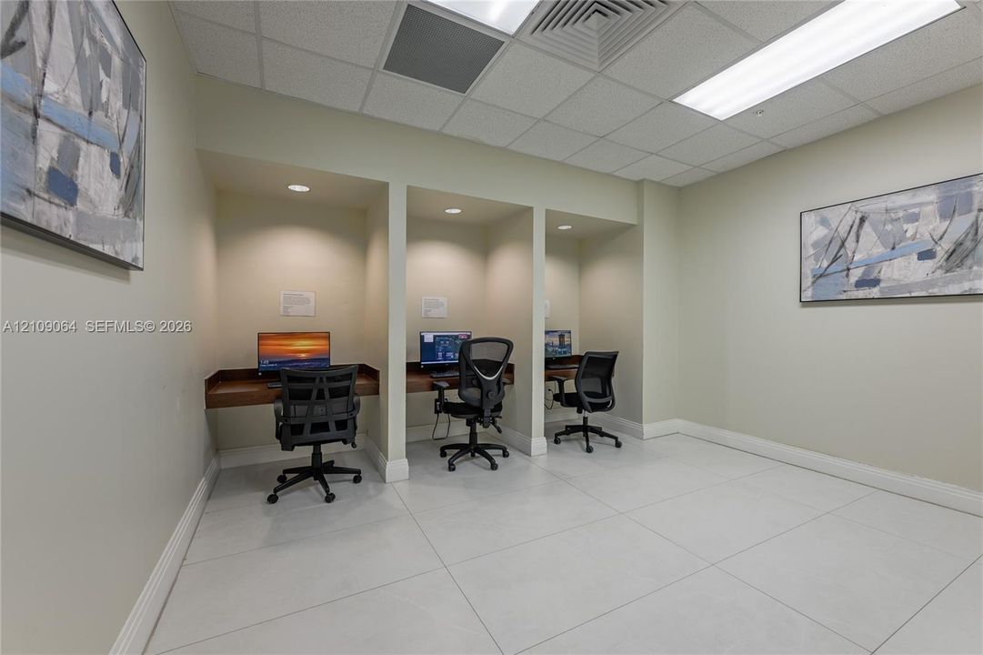 Dedicated workspace area featuring three built-in workstations with recessed lighting and large-format tile flooring