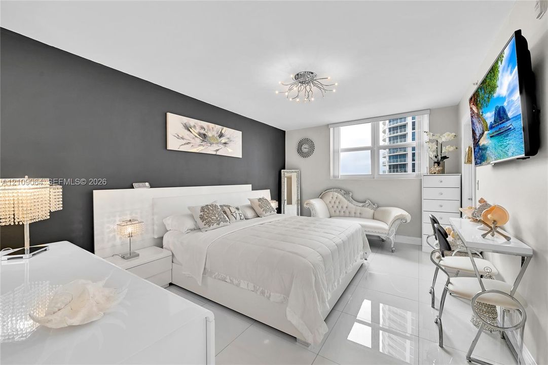 Spacious room featuring high-gloss tile flooring, an accent wall, multi-pane window, and a decorative ceiling-mounted light fixture