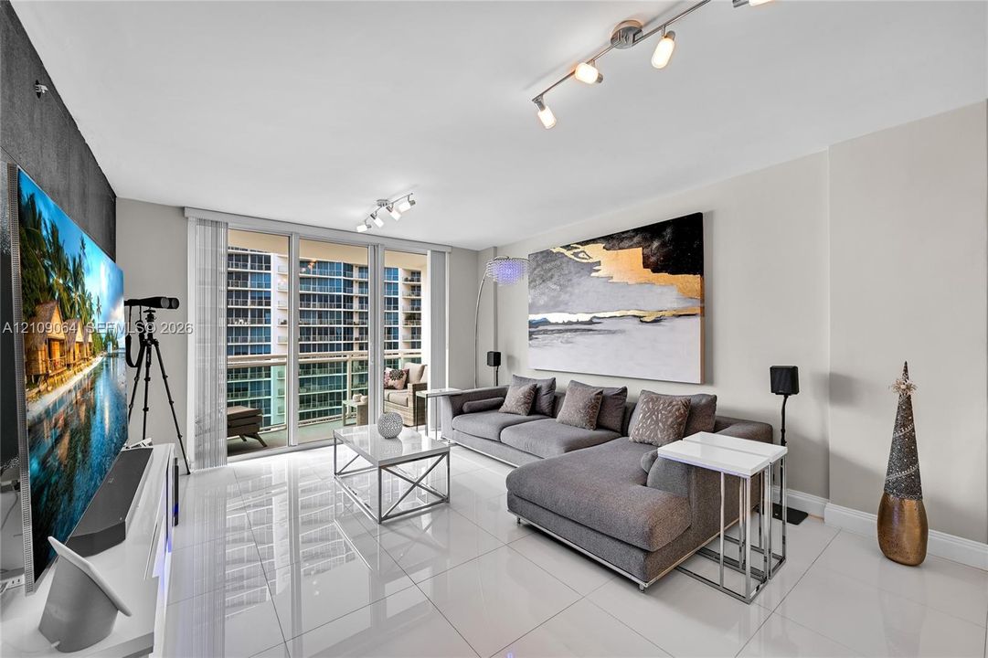 Large-format tile flooring, floor-to-ceiling glass sliding doors, private balcony, and multi-directional track lighting