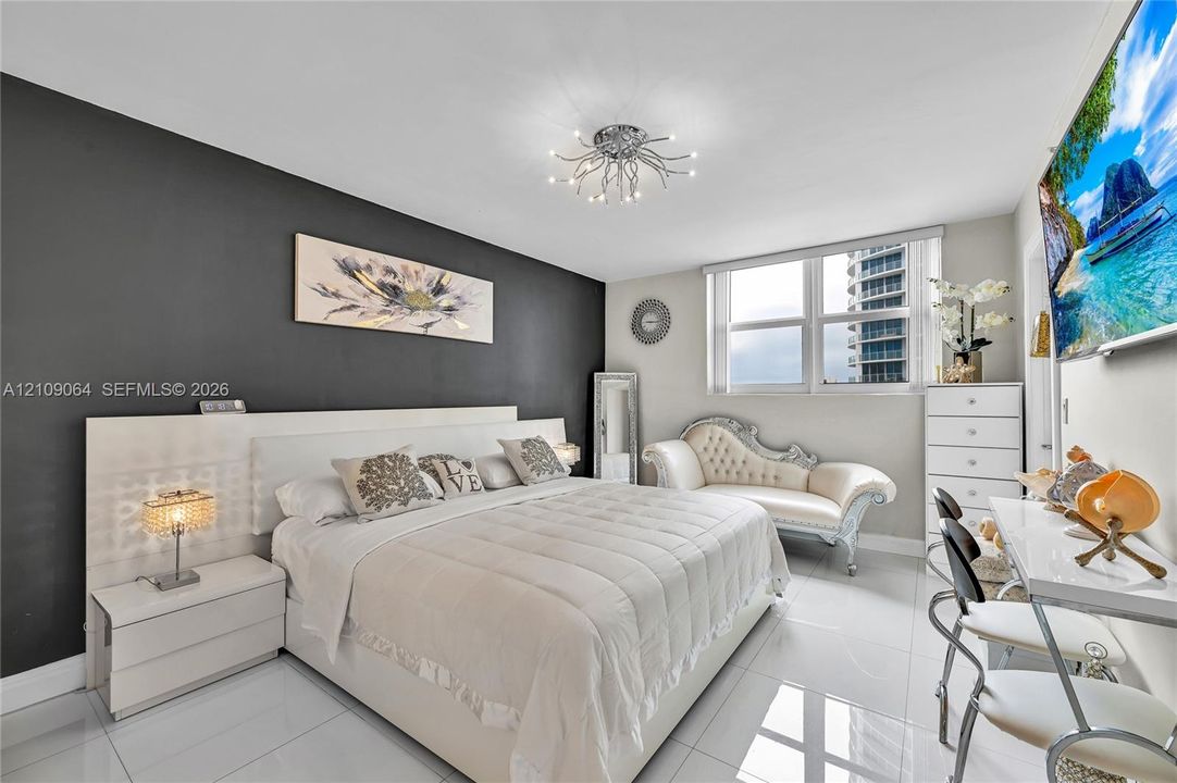 Space featuring a contrasting charcoal accent wall, high-gloss tile flooring, multi-light flush mount ceiling fixture, and a built-in white laminate headboard