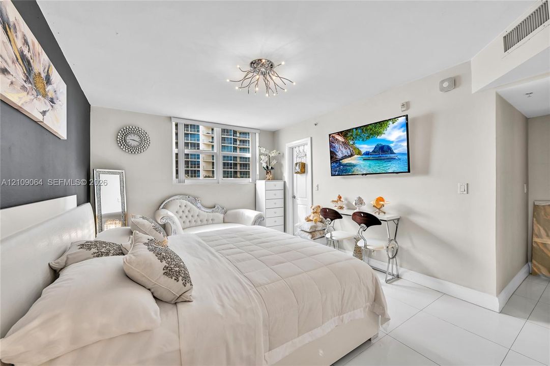 Bright room featuring white tile flooring, a dark charcoal accent wall, and a multi-arm contemporary ceiling light fixture