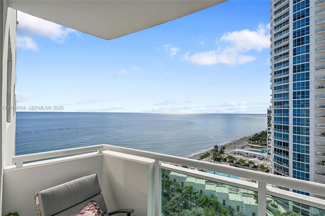 Private balcony featuring a glass panel railing and expansive ocean and coastal scenery