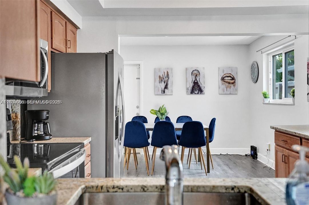 Kitchen featuring wood-finish cabinetry, stainless steel refrigerator, stone countertops, and wood-finish flooring