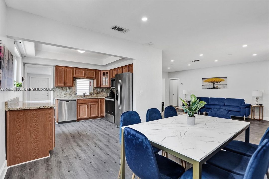 Kitchen featuring wood cabinetry, stone countertops, stainless steel appliances, and recessed lighting with wood-finish flooring