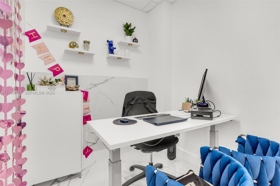 Room interior featuring stone-finish wall cladding and flooring, accented by white floating shelving