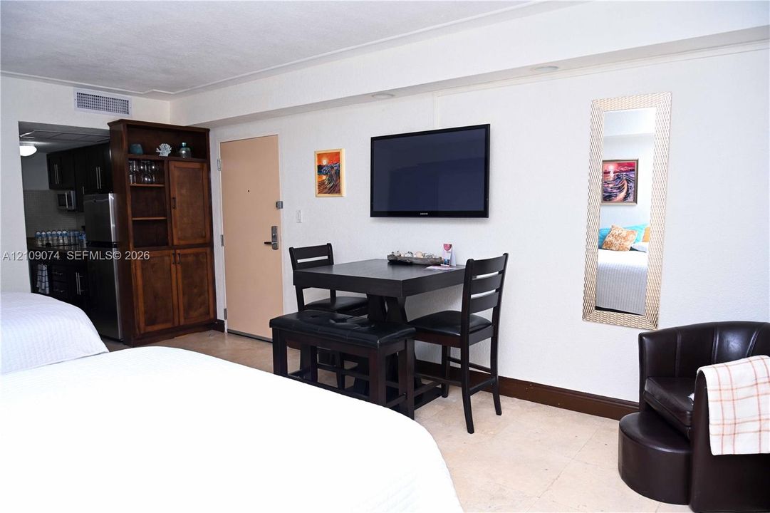 Built-in wood cabinetry, light-toned stone flooring, and a wall-mounted television