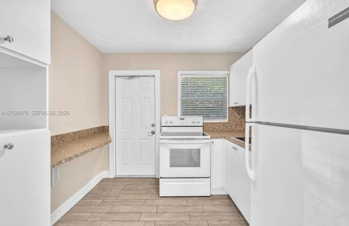 Kitchen featuring white cabinetry, stone-surface countertops, wood-finish flooring, a white freestanding range, and a full-size white refrigerator
