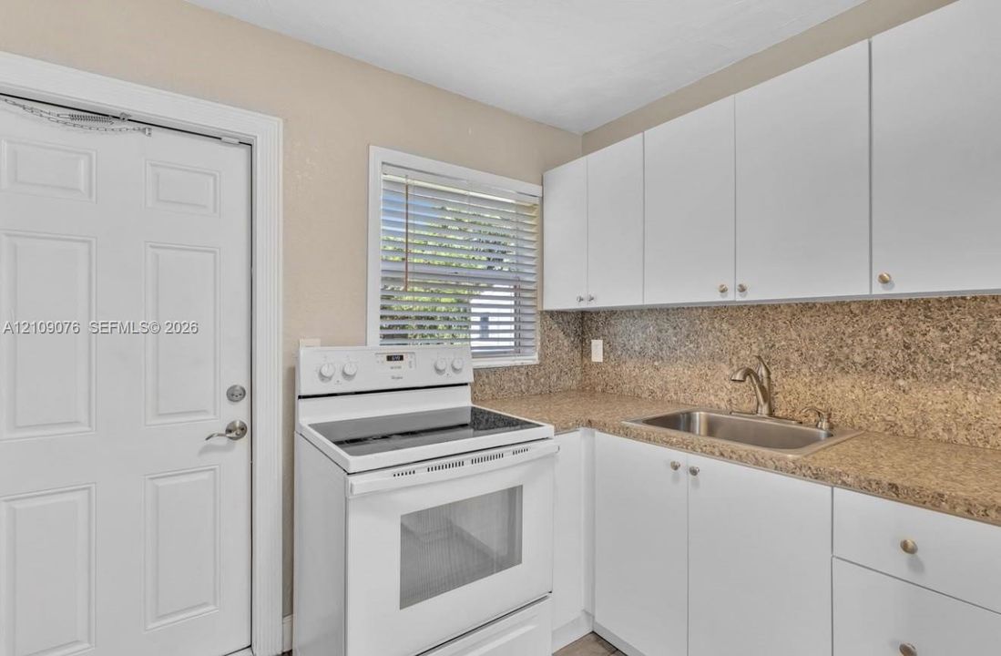 White cabinetry, stone-finish countertops, stainless steel sink with a gooseneck faucet, white electric range, and blinds