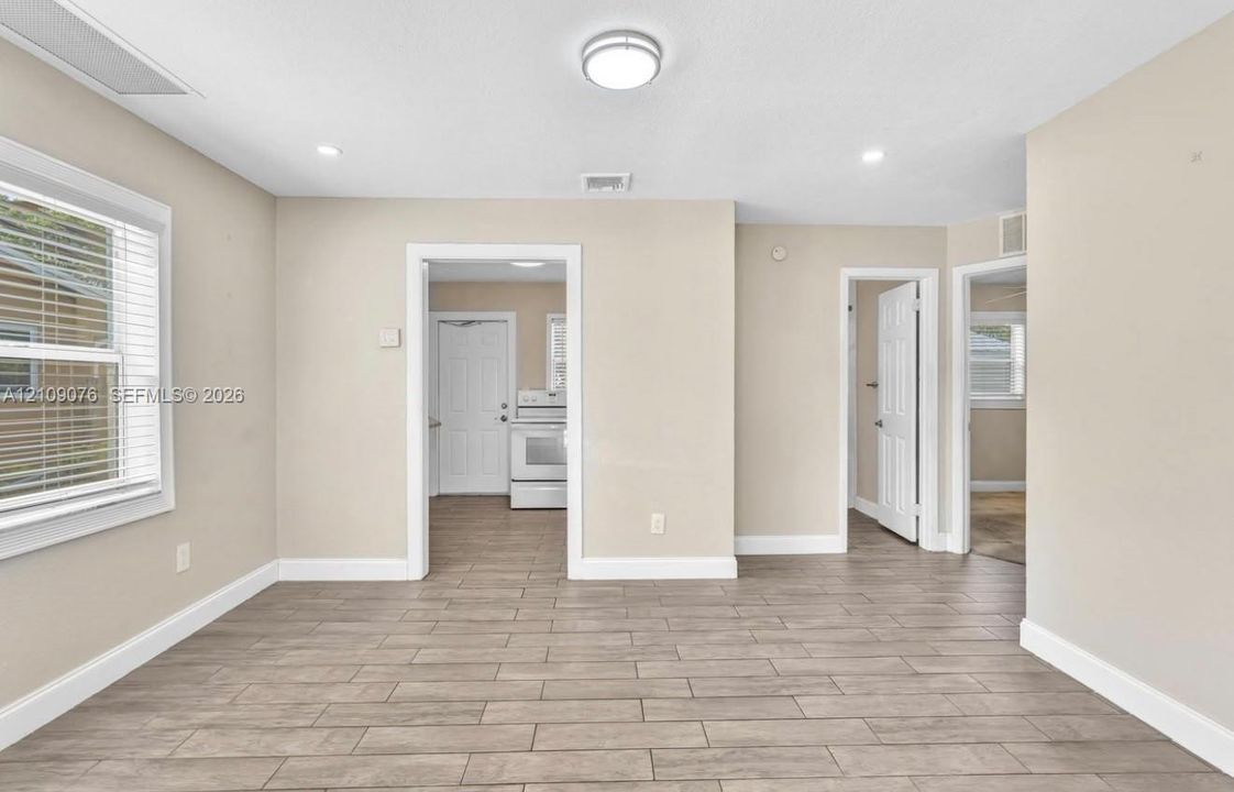 Interior space featuring wood-finish tile flooring, neutral wall paint, recessed ceiling lighting, and multiple interior door frames
