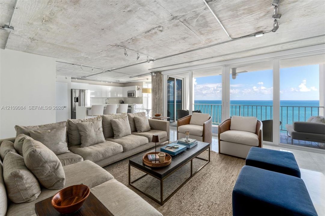 Floor-to-ceiling windows, exposed concrete ceiling, industrial-style drum pendant lighting, polished stone-finish flooring, and exposed concrete structural pillar
