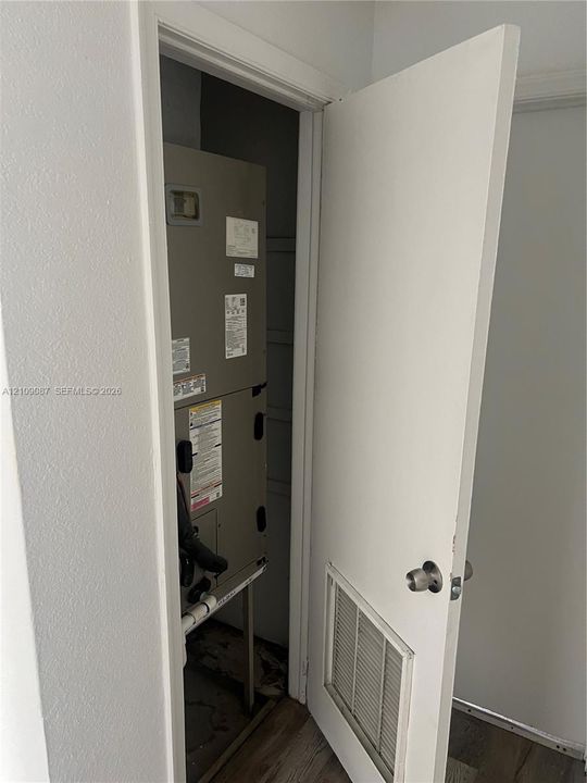 Utility closet featuring an HVAC unit and a louvered ventilation panel door