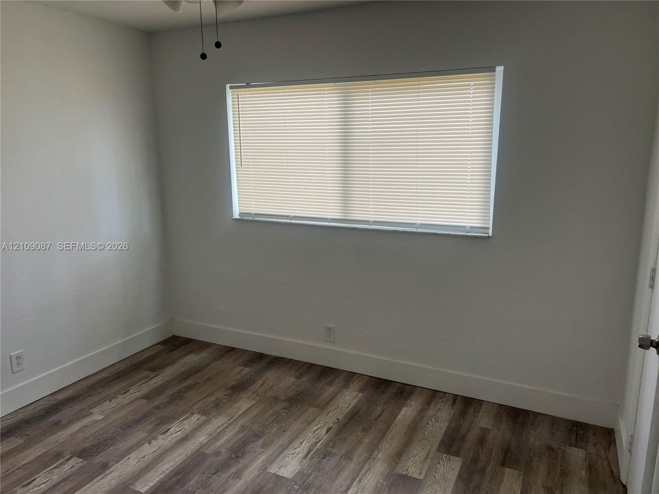 Room featuring wood-finish flooring, neutral wall paint, and a horizontal window with blinds
