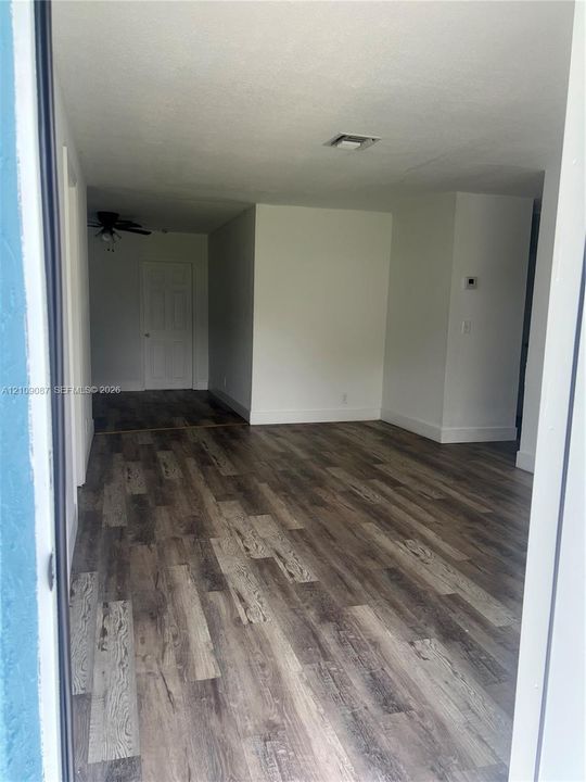 Interior space featuring wood-finish flooring, white walls, and a ceiling-mounted light fixture