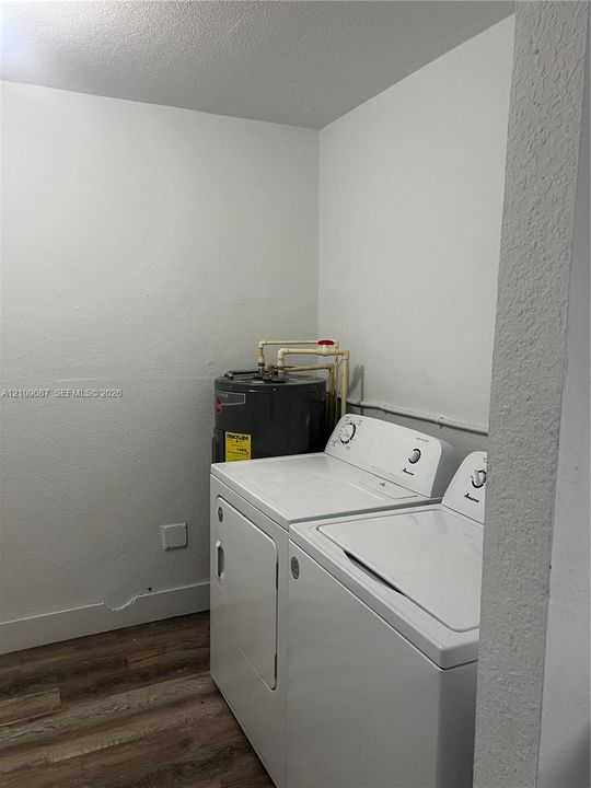 Utility area featuring wood-finish flooring and an upright water heater