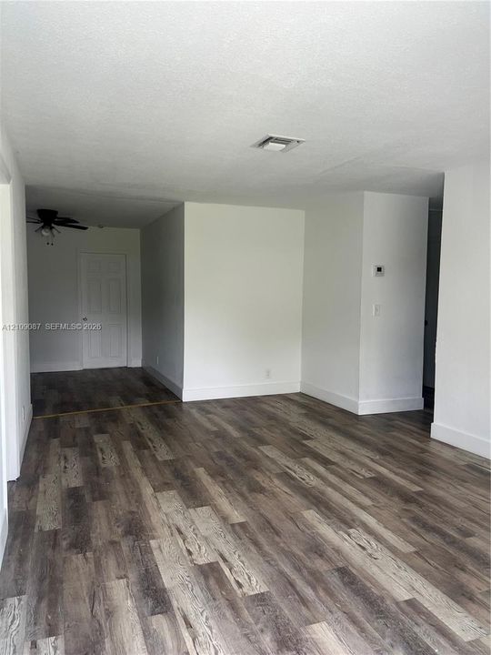 Interior space featuring wood-finish flooring, a multi-panel door, and a ceiling fan with integrated lighting