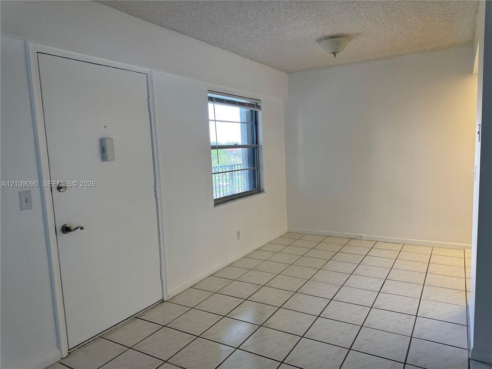 Interior space featuring square floor tiling, a white flush-mount ceiling light, and a single-panel door with metallic hardware