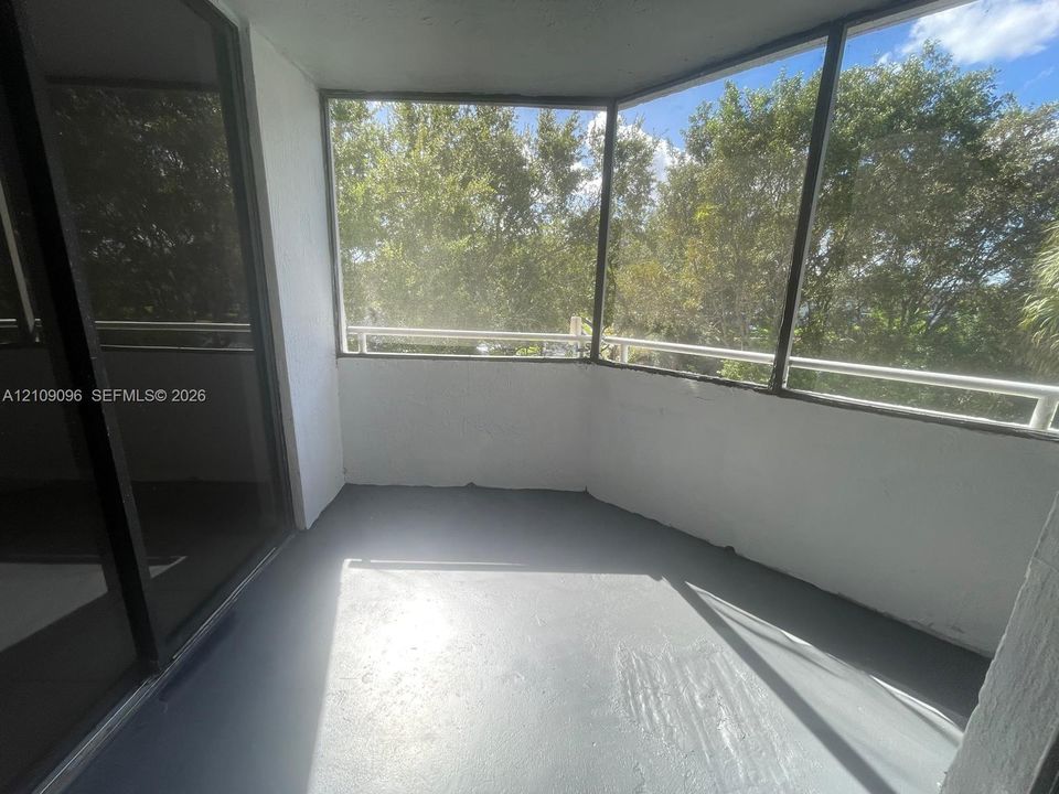 Enclosed balcony featuring screen paneling, painted concrete flooring, and metal railings