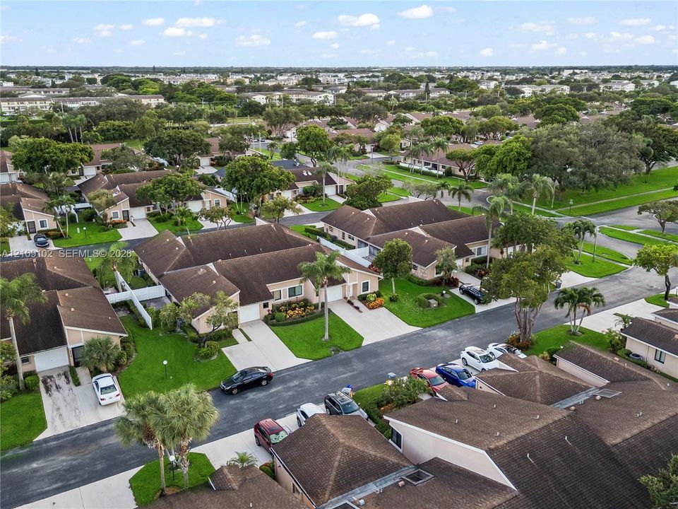 Aerial perspective of a residential community featuring single-story structures with tiled roofs, private driveways, and established tropical landscaping