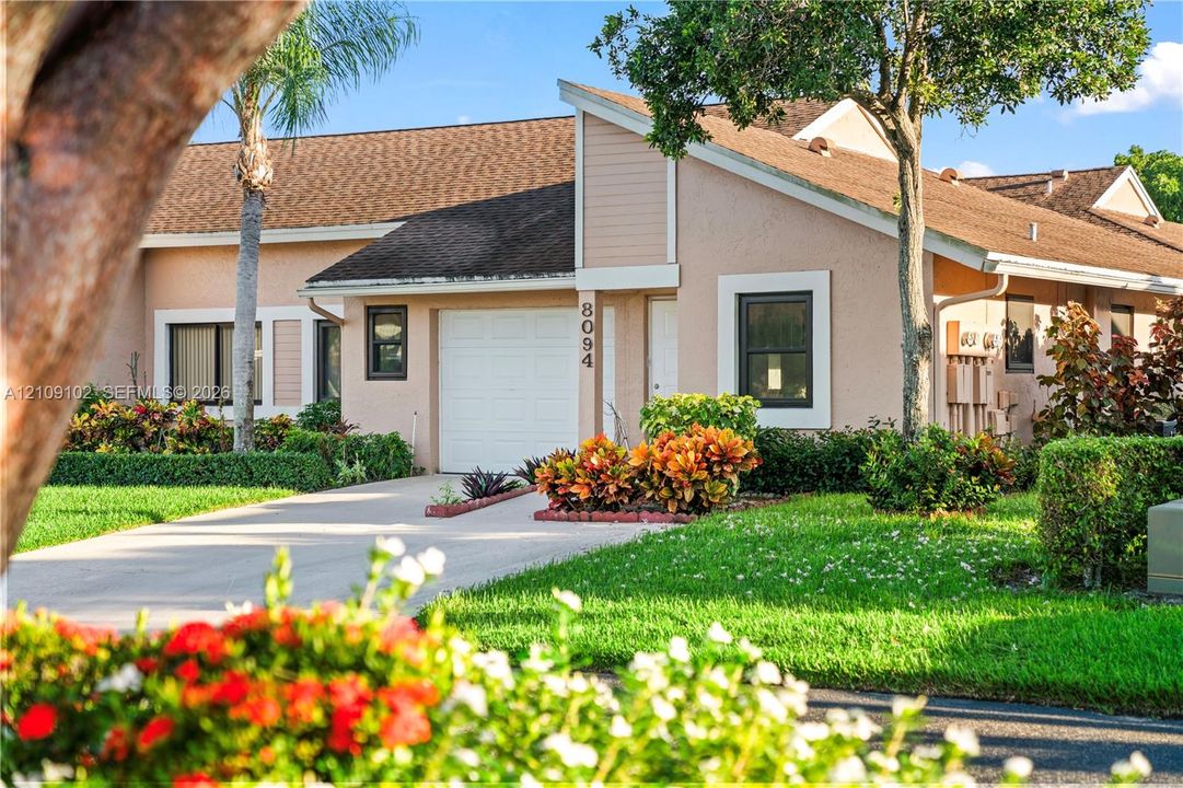 Stucco exterior with a single-car garage, pitched roofline, and landscaped grounds