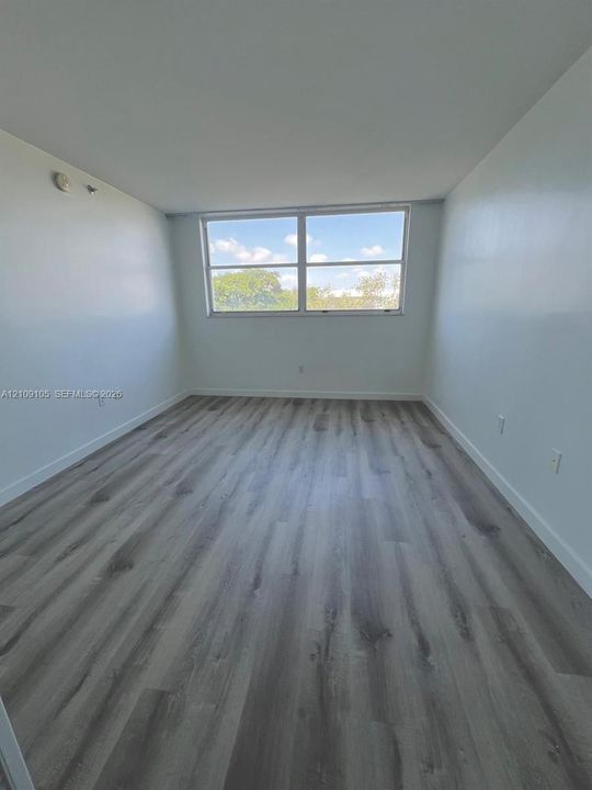 Neutral interior featuring wood-finish flooring, white walls, and a multi-pane window