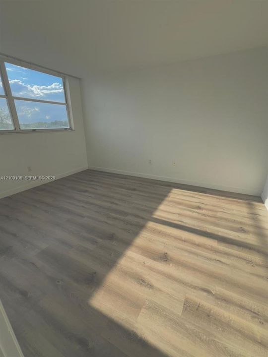 Neutral interior space featuring wood-finish flooring and a multi-pane window