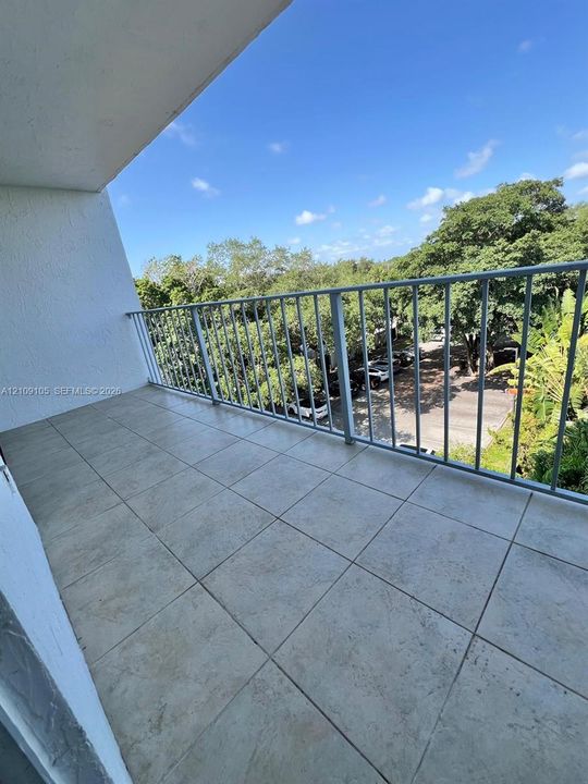Covered balcony featuring neutral tile flooring and a white metal railing