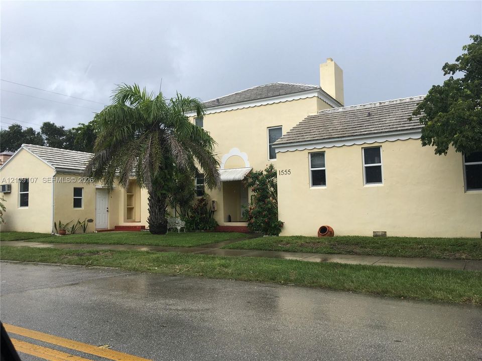 Stucco exterior featuring scalloped roofline trim, a chimney, arched entryway detailing, and a tiled roof