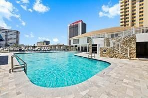 Outdoor swimming pool featuring a paved stone deck, stone exterior wall accents, and metal stair railing