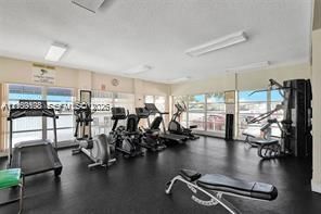 Fitness center featuring expansive floor-to-ceiling windows, uniform rubber flooring, and integrated overhead fluorescent lighting