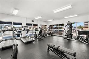 Fitness facility featuring extensive floor-to-ceiling windows, recessed rectangular lighting, and durable rubberized flooring