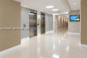 Elevator lobby featuring polished tile flooring, stainless steel elevator doors, recessed ceiling lighting, and decorative wall paneling