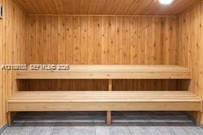 Sauna featuring wood-paneled walls, multi-level built-in wood benches, and tiled flooring