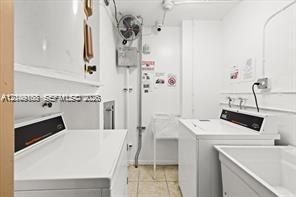 Utility room featuring side-by-side laundry appliances, a built-in utility sink, and stone-finish flooring