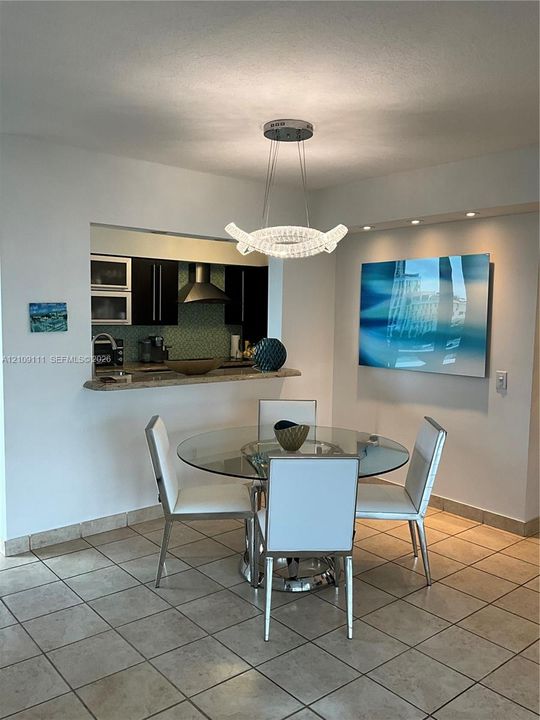 Modern crystal chandelier, stone-surfaced breakfast bar, recessed ceiling lighting, and tile flooring