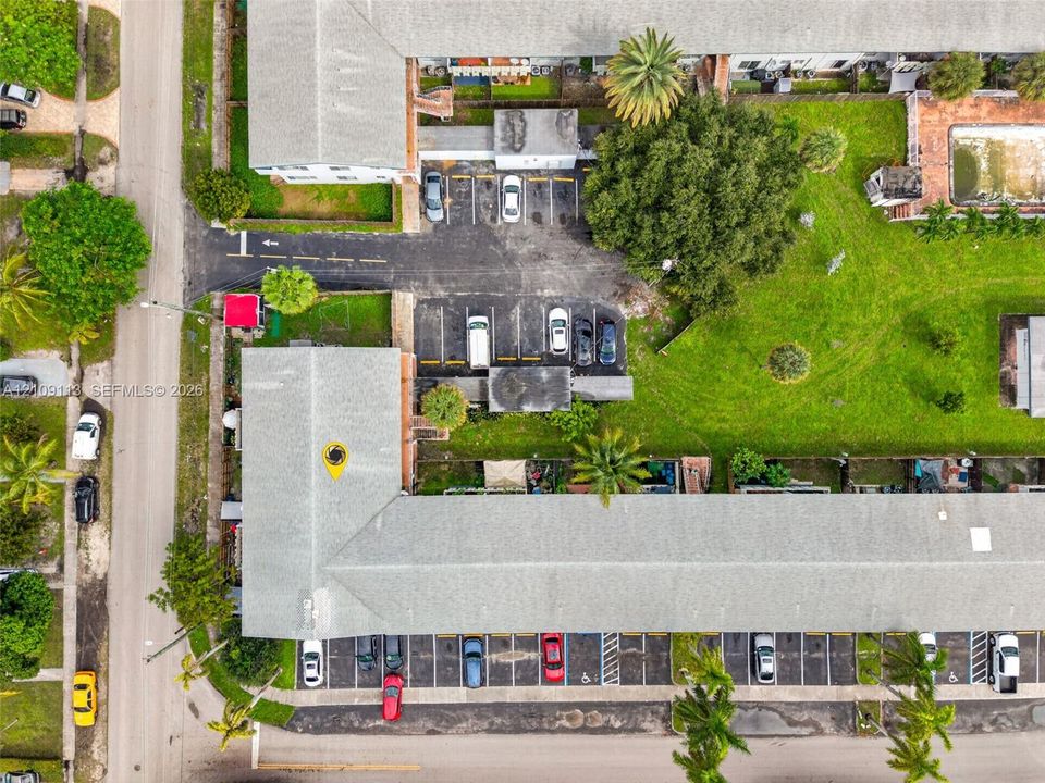Aerial view featuring assigned parking areas, expansive landscaped grounds, and a swimming pool