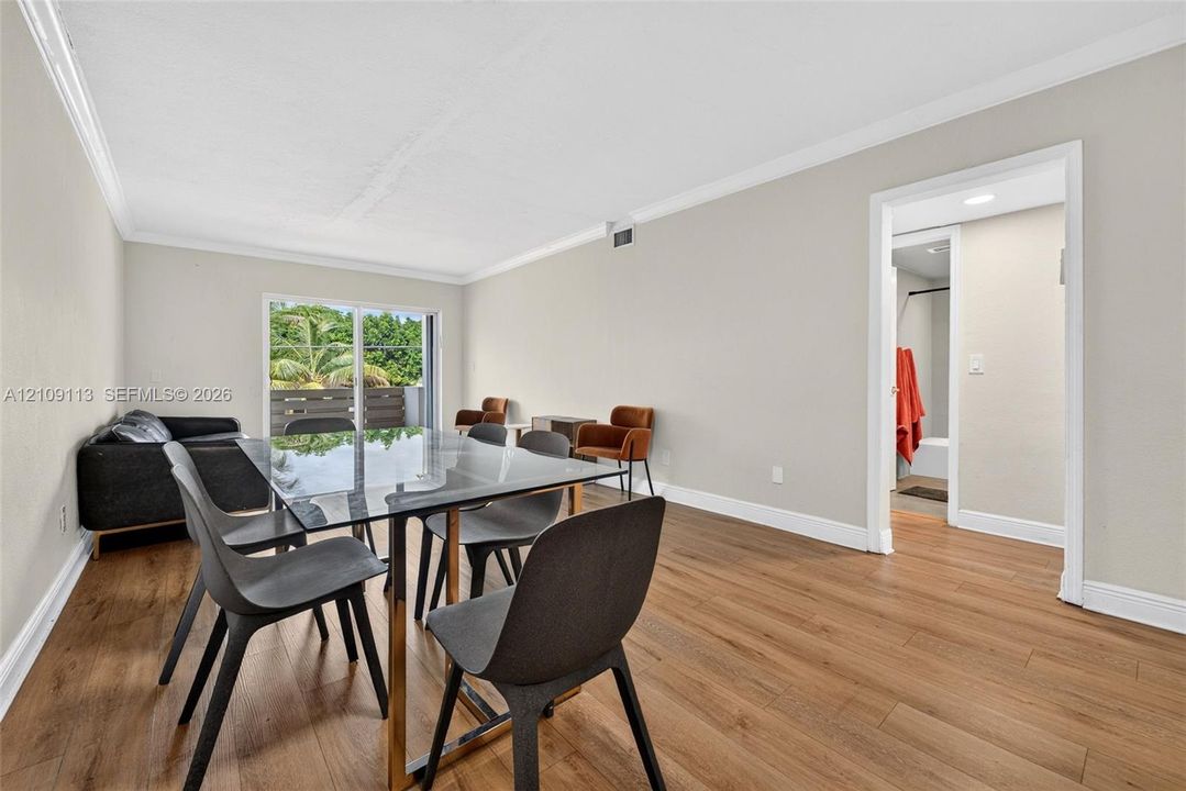 Neutral-toned interior featuring wood-finish flooring, crown molding, and sliding glass doors providing outdoor access