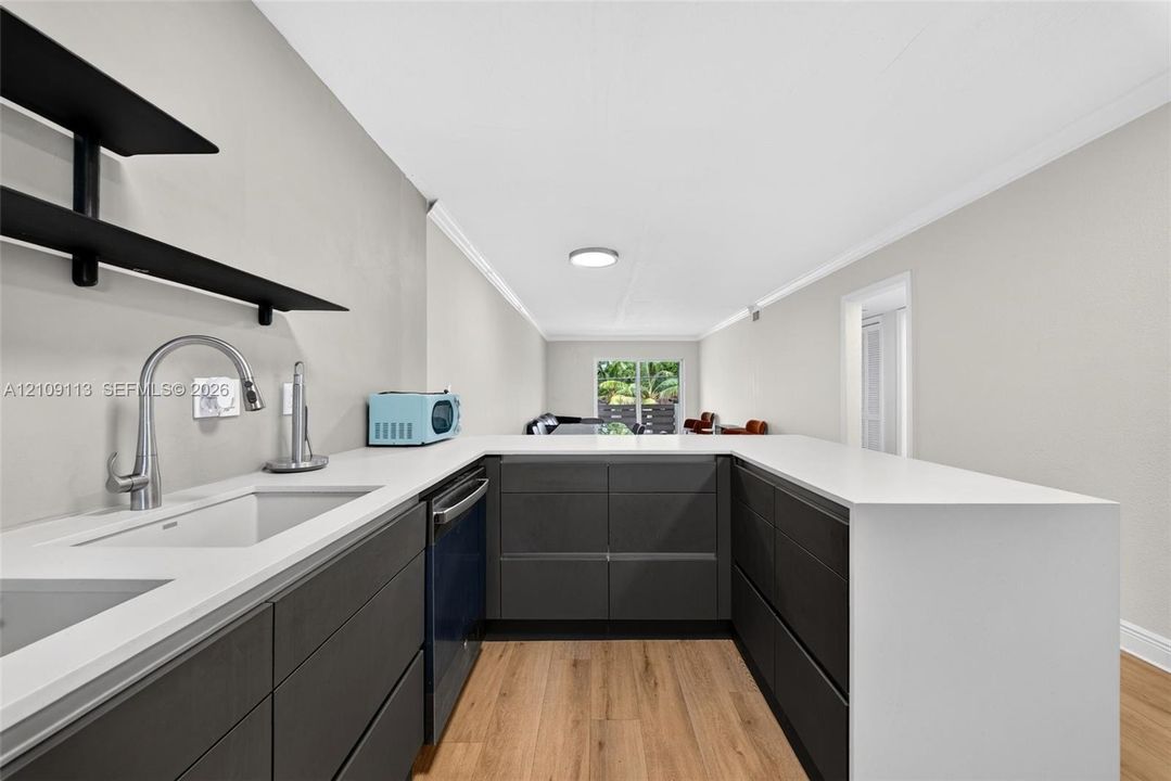 U-shaped kitchen featuring matte charcoal cabinetry, quartz countertops, wood-finish flooring, undermount sink with arched pull-down faucet, and open black wall shelving
