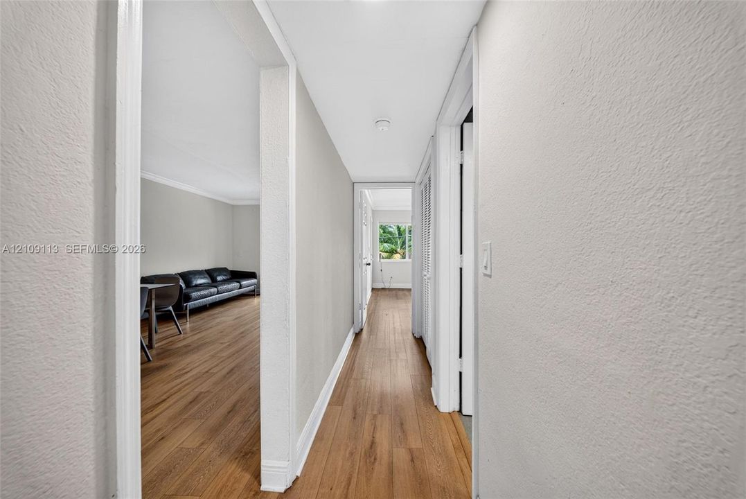 Hallway featuring neutral wall tones, wood-finish flooring, and white door trim