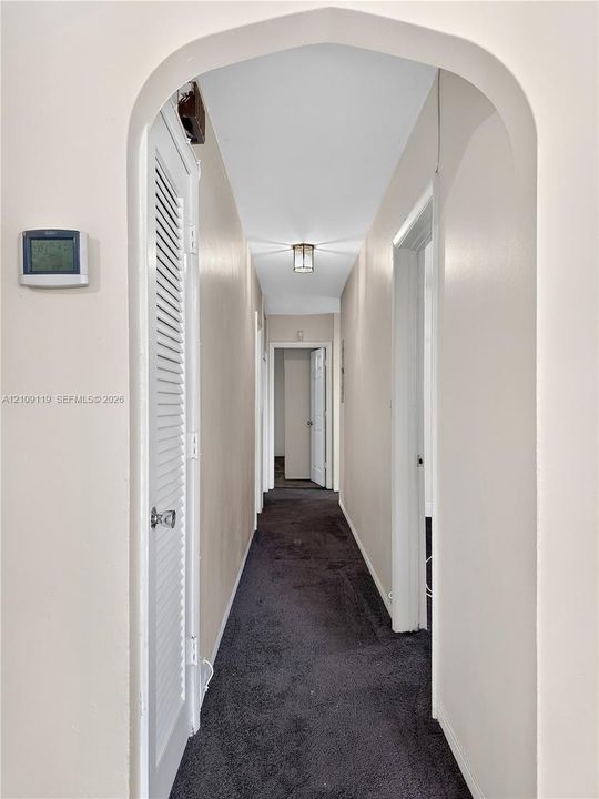 Arched entryway featuring a louvered closet door, recessed flush-mount lighting, and wall-to-wall carpeting