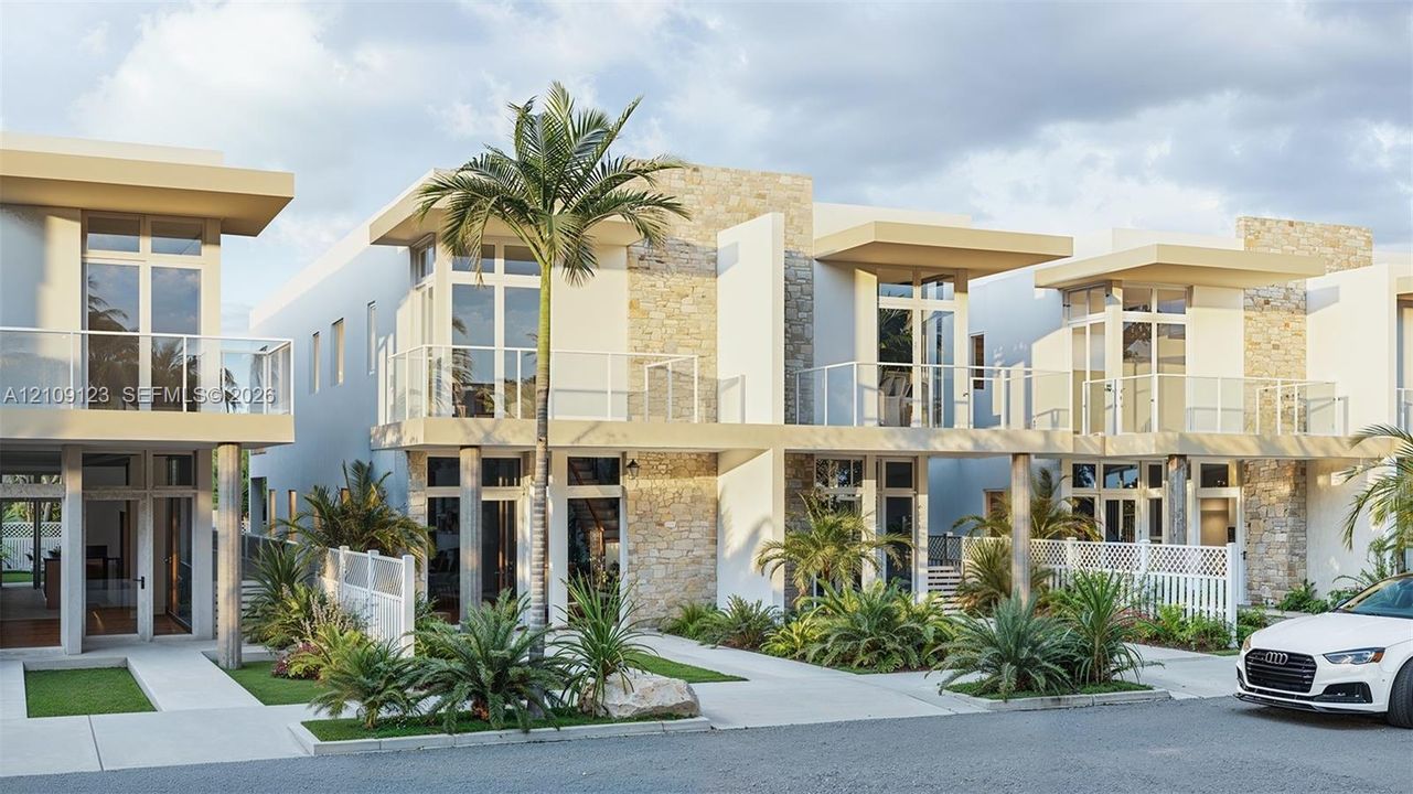 Contemporary multi-unit exterior featuring stacked stone accents, second-story glass-railed balconies, floor-to-ceiling windows, and concrete walkways